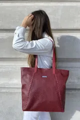 Bolso grande tipo tote de cuero color marrón con costuras decorativas en los laterales, forro interior con bolsillo para celular y bolsillo con cierre. Incluye bolsillo trasero con cierre y correas largas para colgar del hombro.