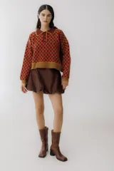Sweater de punto color beige con diseño de rombos marrones, cuello polo con botones y mangas largas abullonadas.