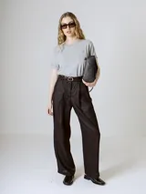 Pantalón negro de corte ancho y tiro alto, con pinzas en la cintura y bolsillos laterales.