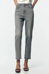 Pantalón de jean azul de tiro alto, corte mom fit, tobillero y con cinco bolsillos. Cierre frontal con cremallera y botón.