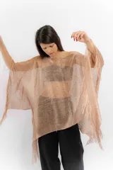 Poncho tejido color cobre con apliques de piedras y flecos.