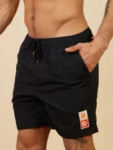 Short de baño negro con cintura elástica ajustable con cordón naranja. Presenta un pequeño estampado en la pierna derecha.