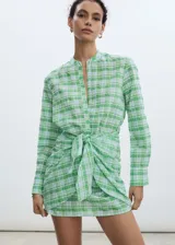 Vestido corto camisero con estampado de cuadros verdes y celestes, cuello mao, mangas largas abotonadas y lazo en la cintura.