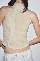 Top color crema de tejido de punto con cuello halter fluido y hombros descubiertos. Detalle de hilo metalizado.