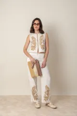 Pantalón de lino color crudo con bordado floral color camel en el ruedo y costados. Tiene bolsillos laterales y cintura elástica.