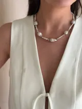 Collar corto de perlas de río alargadas y ovaladas, con cuentas de acero quirúrgico y bolitas con baño de oro. Cierre con cadena de acero quirúrgico y gancho para regular el largo.