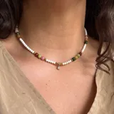 Gargantilla corta de cuentas pequeñas color blanco, con cuentas grandes de colores (rosa, verde, marrón y amarillo) y dije de cristal transparente.