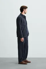 Pantalón azul marino de corte recto, confeccionado en tejido de algodón y lino. Tiene cintura elástica ajustable con cordón, bolsillos delanteros y traseros de vivo.