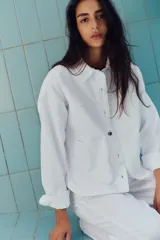 Cazadora de denim verde oliva, con cuello solapa, manga larga, bolsillos delanteros de plastrón y cierre frontal con botones metálicos.