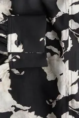 Blusa oversized con cuello elevado fruncido, abertura en V adelante y bajo recto. Mangas globo largas de corte raglán con abertura y botón en los puños.
