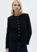 Chaqueta negra de tweed con cuello redondo, cierre frontal con botones plateados, mangas largas con puños abotonados, dos bolsillos de parche frontales y terminaciones deshilachadas.