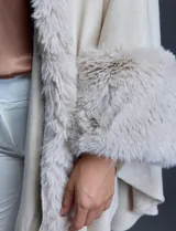 Ruana tejida color crema de la marca Adrienne Vittadini, con cuello, delantera y puños con aplique en símil piel. Delantera con abertura central y botón trenca.