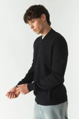 Campera de tejido negro con textura en el frontal, escote redondo y puños ajustados.