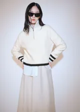 Sweater de punto grueso color crema con cuello alto con cierre de cremallera y detalle de rayas marrones en contraste en mangas y ruedo.