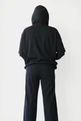Buzo negro con capucha y cordones ajustables, mangas largas con puños ajustados y estampado frontal de flores amarillas y blancas con texto en blanco.