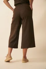 Pantalón palazzo color beige, de tiro alto, con bolsillos laterales y largo a la pantorrilla.