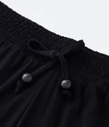 Pantalón negro de crepé, modelo pantacourt, con lazo en la cintura y bajo asimétrico.