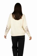 Sweater color crema con cuello redondo y diseño de flores bordadas en color topo en el frente y las mangas.