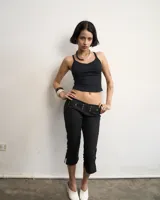 Pantalón capri negro de gabardina elastizada, corte al cuerpo y largo 3/4. Detalle de hilera de argollas en la cintura y abertura en el ruedo.