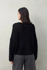 Sweater negro calado con diseño de líneas diagonales en relieve y mangas acampanadas.