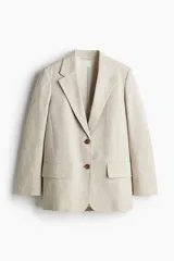 Blazer color beige de tejido de espiguilla de mezcla de algodón y lino. Modelo de botonadura sencilla con hombreras, solapas de muesca y bolsillos ribeteados con solapa adelante. Forro en gasa de algodón.