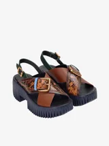 Sandalias de cuero con plataforma, tiras cruzadas y hebilla metálica.