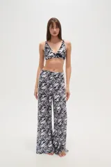 Pantalón largo de tela fluida con estampado de cebra en tonos rosa y fucsia. Tiene corte ancho y aberturas laterales con detalle de argollas.