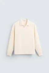 Polo color crema de manga larga con cuello solapa y abertura frontal.