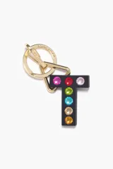 Llavero de silicona negra con forma de letra 'T' decorada con cristales incrustados en diversos colores. Cuenta con un sistema de sujeción compuesto por un aro y un mosquetón metálicos en tono dorado.