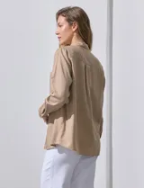 Camisa blanca de lyocell, marca Dash. Tiene cuello con solapa, abertura central con botones, mangas largas regulables con presilla y botón, y dos bolsillos delanteros aplicados.