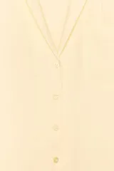 Camisa color amarillo pálido de tejido fluido, con cuello solapa, escote pico, manga corta, bolsillo de parche en el pecho y cierre frontal con botones.