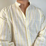 Camisa de lino a rayas amarillas y blancas, con cuello mao y corte regular.