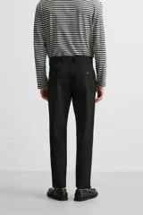 Pantalón slim fit negro confeccionado en tejido con elasticidad en ambas direcciones. Cuenta con bolsillos frontales y traseros de vivo con botón. Cierre frontal con cremallera y botón.