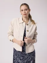 Chaqueta color beige de corte recto, con cuello camisero, cierre frontal con botones, dos bolsillos de parche en el pecho y mangas largas con puños abotonados. Confeccionada en mezcla de lino y algodón.