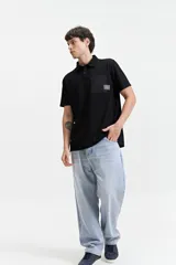 Remera polo negra con bolsillo de nylon en el pecho y logo bordado. Corte regular.
