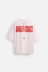 Camiseta rosa de corte holgado, cuello redondo y manga corta. Estampado frontal con texto en rojo "Amalfi Coast" y estrellas.