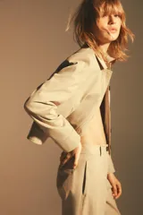 Chaqueta color beige de cuello solapa y manga larga con hombreras acabada en puño. Presenta bolsillos laterales y falso bolsillo de vivo en pecho. Cierre frontal con botones.