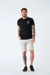 Bermuda color beige de corte chino, con bolsillos laterales, cierre con cremallera y botón, presillas para cinturón y logo bordado. Confeccionada en lino y algodón.