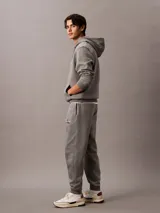 Pantalón de jogging gris con cintura elástica, bolsillos laterales y logo de Calvin Klein Jeans en la pierna. Confeccionado en mezcla de algodón y poliéster.