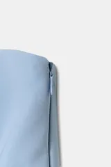 Top blanco de tejido elástico, sin mangas y con escote recto. Tiene corte peplum en la parte inferior y cierre con cremallera oculta en la costura.