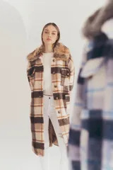 Tapado largo con estampado a cuadros en tonos marrón, beige y blanco. Presenta cuello con solapa y detalle de piel sintética.