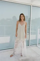 Vestido largo color beige, de punto fino, con escote en V y tirantes finos. La parte inferior es de encaje blanco.