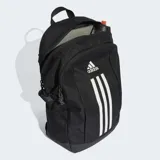 Mochila deportiva Adidas de color negro con tres franjas verticales blancas en el frente y logo de la marca en la parte superior. Cuenta con bolsillos laterales de malla y base reforzada.