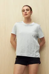 Remera blanca de algodón liviano con textura sutil, manga corta y cuello redondo.