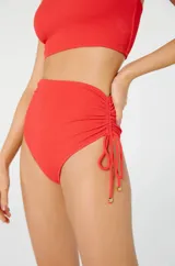 Bikini de una sola manga color rojo, con detalle de tiras ajustables en la parte inferior.