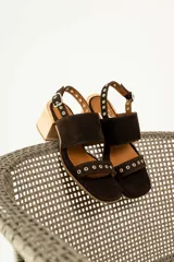 Sandalias de tacón de madera con tiras de gamuza marrón y detalles de tachas metálicas.