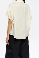 Camisa corta color crema de 100% algodón con cuello camisero y manga corta murciélago. Cierre frontal con botonadura.