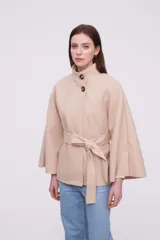 Chaqueta color beige con cuello alto, mangas anchas y cinturón.