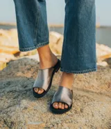 Sandalias bajas de cuero vacuno color negro, con suela de goma y horma de punta redonda. Producto de horma chica, se recomienda pedir un talle más.