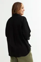 Camisa color beige de corte amplio, con cuello clásico, manga larga y bolsillo en el pecho.